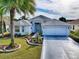 Well-maintained single-story home with manicured lawn, concrete driveway, and a mature palm tree in the front yard at 320 Rhapsody Path, The Villages, FL 32162