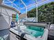 Outdoor hot tub with an umbrella and chairs, enclosed by a screened in porch at 320 Rhapsody Path, The Villages, FL 32162