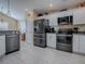 Kitchen with white cabinetry, stainless steel appliances, tile floors and a pantry door at 320 Rhapsody Path, The Villages, FL 32162