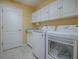 Functional laundry room with modern washer and dryer and overhead cabinets at 320 Rhapsody Path, The Villages, FL 32162