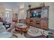 Spacious living room with a wooden entertainment center, leather seating, and a glass-topped coffee table on a patterned rug at 320 Rhapsody Path, The Villages, FL 32162