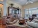 Cozy living room with a wooden entertainment center, plush seating, a ceiling fan, and sliding glass doors at 320 Rhapsody Path, The Villages, FL 32162