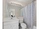 Bright bathroom featuring white vanity, large mirror, and seashell-themed shower curtain at 3637 Hawkshead Dr, Clermont, FL 34711