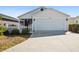 Front view of house with white garage door and picket fence at 3818 Zentko St, The Villages, FL 32163