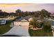 Aerial view of a charming home with lush landscaping, palm trees, and a spacious driveway at sunset at 4515 Biggs Pl, The Villages, FL 32163