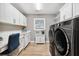 This laundry room features light grey walls, white cabinets, wood look tile, and front loading washer and dryer at 4515 Biggs Pl, The Villages, FL 32163