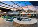 Outdoor swimming pool area with a screened-in enclosure, hot tub, and multiple seating areas at 4515 Biggs Pl, The Villages, FL 32163