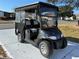 Image of a covered black golf cart, in good condition, on a sunny day at 525 Bonita Dr, Lady Lake, FL 32159