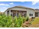 Tan house exterior with screened patio and landscaping at 6206 Dingman Way, The Villages, FL 32163