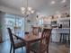 Bright dining area with wood table, modern chandelier, and access to a screened lanai overlooking the water at 802 Nancy Dr, The Villages, FL 32163