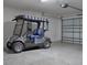 Clean garage featuring a gray golf cart with blue striped seats, and an overhead garage door at 802 Nancy Dr, The Villages, FL 32163