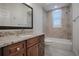 Bathroom with granite countertop, brown vanity, and bathtub at 858 Pinckney Ln, The Villages, FL 32162