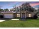 House exterior featuring a one-story home with a garage and well-manicured lawn at 870 Vindale Rd, Tavares, FL 32778