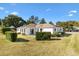 Spacious backyard with an expansive lawn, mature shrubs, and a rear building elevation at 9184 Se 135Th St, Summerfield, FL 34491