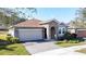 Charming single-story home with stone accents, brick driveway, manicured lawn, and attached two-car garage at 96 Silver Maple Rd, Groveland, FL 34736