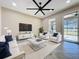 Bright living room with white furniture, ceiling fan, and sliding glass doors leading to a patio at 96 Silver Maple Rd, Groveland, FL 34736