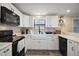 Well-lit kitchen featuring a farmhouse sink, white cabinets, and black appliances at 24450 Ne 127Th St, Salt Springs, FL 32134