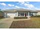 Gray house with white garage door and red front door, landscaped lawn at 11579 Se 172Nd Loop, Summerfield, FL 34491