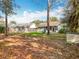 Large backyard featuring a shed, screened in porch and a partially fenced yard with mature trees and falling leaves at 11744 Oswalt Rd, Clermont, FL 34711