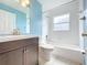 Bright bathroom featuring blue walls, a white tub and toilet, and a vanity with dark wood cabinets at 11744 Oswalt Rd, Clermont, FL 34711