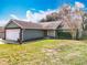 Well-manicured front yard with a cozy one-story home featuring a brick-accented garage and lush greenery at 11744 Oswalt Rd, Clermont, FL 34711