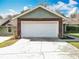 Close-up of a two-car garage featuring a white door, brick accents, and well-maintained landscaping at 11744 Oswalt Rd, Clermont, FL 34711