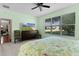 Green main bedroom with dark dresser featuring large TV and a large window with exterior view at 13914 Se 96Th Cir, Summerfield, FL 34491