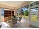 Relaxing sunroom with tile flooring, glass table, and views of the lush backyard at 13914 Se 96Th Cir, Summerfield, FL 34491