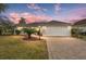 Attractive home exterior at dusk, featuring a paved driveway and landscaping at 1514 Vandam St, The Villages, FL 32162