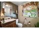 Elegant bathroom featuring a decorative vanity, toilet, mirror, and a window with outdoor views at 1702 N County Road 452, Eustis, FL 32726