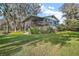 Exterior view of the home with screen porch, balcony, mature trees, and well-kept lawn at 1702 N County Road 452, Eustis, FL 32726