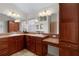 Bathroom with a double-sink vanity, wood cabinets, a large mirror, and tile flooring at 2017 Royal Elm Rd, The Villages, FL 32162