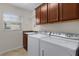 Functional laundry room with washer, dryer, storage cabinets, and natural light at 2017 Royal Elm Rd, The Villages, FL 32162