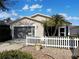 Tan house with gray garage door and white picket fence at 2067 Broyhill Ave, The Villages, FL 32162