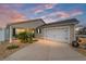 Tan house with white garage door, landscaping, and a walkway at 2222 Southwood Dr, The Villages, FL 32162