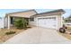 Tan house with white garage door, landscaping, and a walkway at 2222 Southwood Dr, The Villages, FL 32162