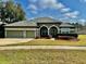 Green house with three-car garage and manicured lawn at 225 Sutherland Ct, Apopka, FL 32712