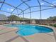 Screened in pool has a blue tile border and manicured landscape at 225 Sutherland Ct, Apopka, FL 32712