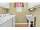 This laundry room features a utility sink, storage cabinets and a window for natural light at 2303 Nehaul Ter, The Villages, FL 32162