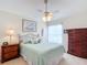 Bedroom with a queen bed, ceiling fan, dresser, and large window at 2849 Leicester Ter, The Villages, FL 32162