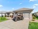 Home exterior featuring a well-maintained lawn, landscaping, and golf cart parked in the driveway at 3183 Hatch Ln, The Villages, FL 32162