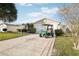 Extended driveway features decorative compass inlay, leading to a two-car garage, with a green golf cart at 3319 Thorncrest Dr, The Villages, FL 32162