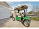 A green golf cart sits on the driveway, with covered seating, custom wheels, and street-legal lights at 3319 Thorncrest Dr, The Villages, FL 32162