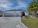 Beautiful single-story home with a three-car garage, decorative driveway, and tropical landscaping at 4774 Cosentino Ct, The Villages, FL 32163