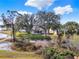 Expansive backyard view, with a patio partially obscured by trees, sits in a serene, nature-filled setting at 5338 Tigers Tail, Leesburg, FL 34748