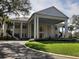 Elegant white two-story clubhouse featuring stately columns, lush landscaping, and grand entrance at 5338 Tigers Tail, Leesburg, FL 34748