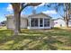 View of the rear sunroom with large picture windows and a large tree in the back yard at 5338 Tigers Tail, Leesburg, FL 34748