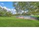 Beautifully landscaped tennis courts surrounded by green grass, trees, and a clear blue sky at 5338 Tigers Tail, Leesburg, FL 34748