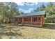 Quaint log cabin with a covered porch and green metal roof set in a natural landscape at 775 Abeble Rd, Lady Lake, FL 32159