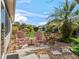 Seating area in landscaped backyard, featuring two pink chairs, lush greenery, and a clear blue sky at 8662 Se 133Rd Ln, Summerfield, FL 34491